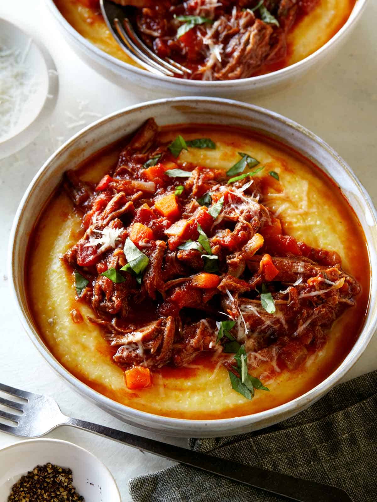 Braised beef ragu in two bowls with forks on the side.