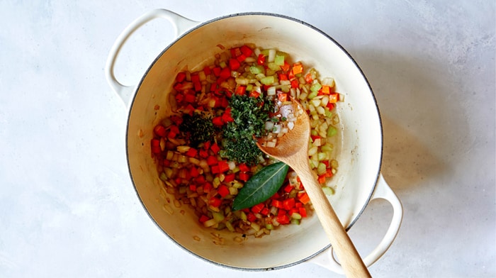 Veggies and herbs in a stock pot to make braised lamb shanks.