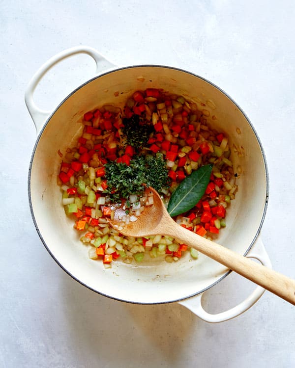 Veggies and herbs in a stock pot to make braised lamb shanks.