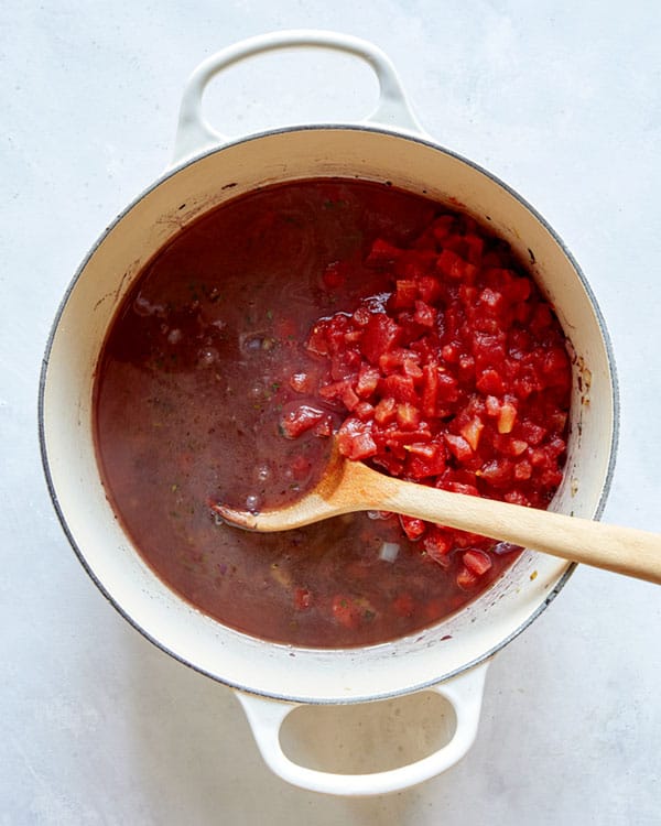 Tomatoes and stock in a pot to make braised lamb shanks.