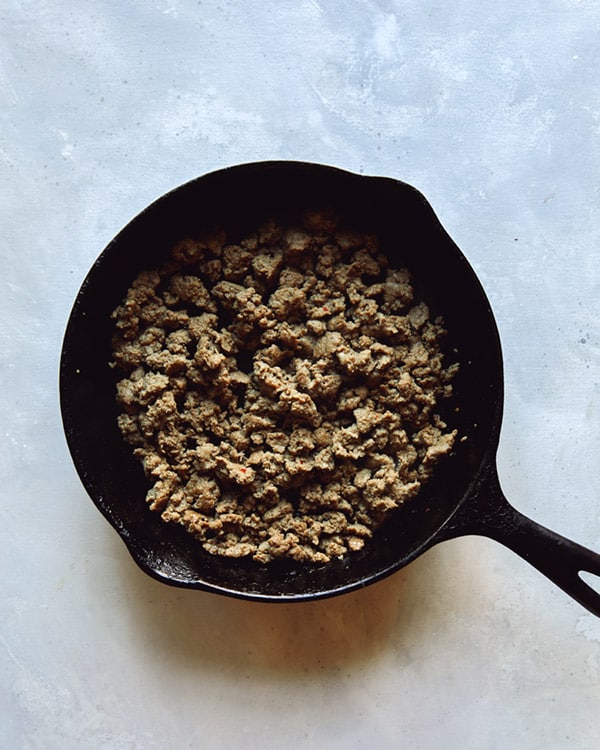 A cast iron skillet with breakfast sausage browned in it for a breakfast casserole recipe.