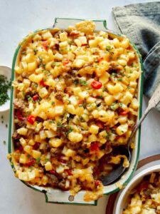 Breakfast casserole with a scoop out and some in a bowl next to it.