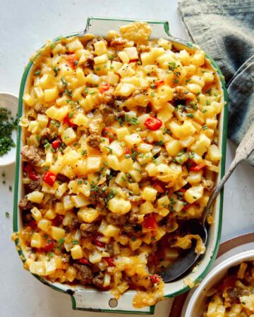 Breakfast casserole with a scoop out and some in a bowl next to it.