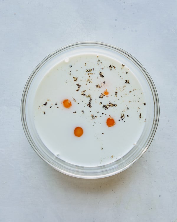 Eggs and milk in a glass bowl to make breakfast casserole.