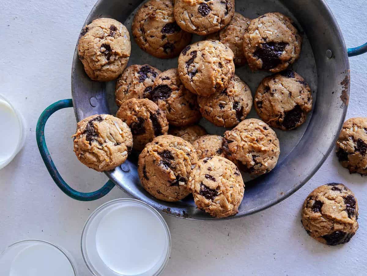 A plate of chai, chocolate chip, coconut, cookies and milk.
