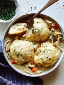 Chicken and Dumplings recipe in a bowl with a spoon taken a piece out of one of the dumplings.