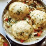 Chicken and dumplings recipe made in two bowls with garnishes on the side.