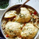 Chicken and Dumplings recipe in a bowl with a spoon taken a piece out of one of the dumplings.