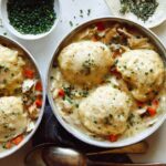 Chicken and dumplings recipe made in two bowls with garnishes on the side.