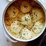 A pot of chicken and dumpling recipe with a napkin next to it.