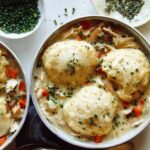 Chicken and dumplings recipe made in two bowls with garnishes on the side.