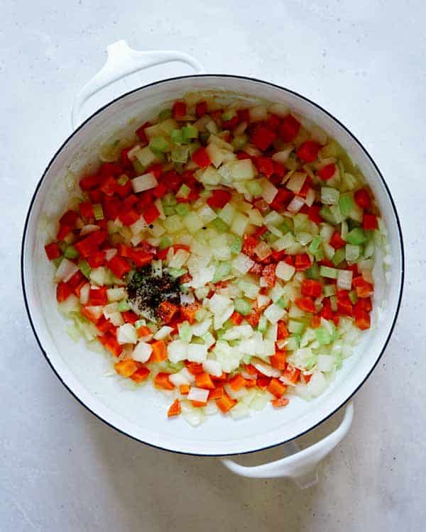 A pot with cooking vegetables and salt and pepper to make chicken and dumplings.