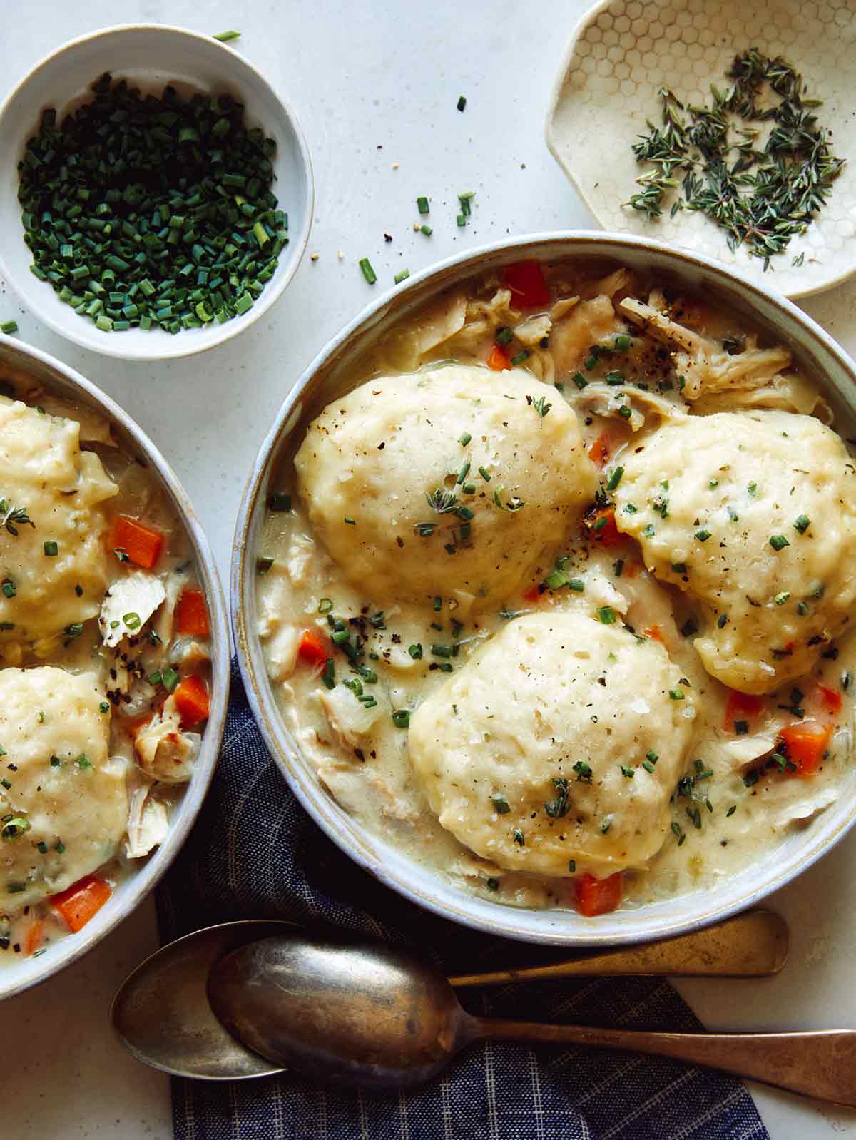 Chicken and dumplings recipe made and in two bowls with spoons on the side.