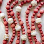 DIY Christmas garland made of wood beans laid out on a surface.