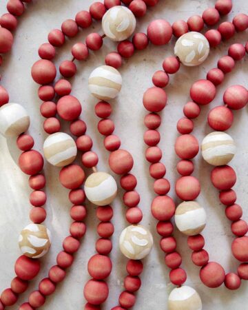 DIY Christmas garland made of wood beans laid out on a surface.