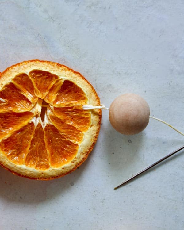 A wooden bead at the end of a citrus garland. 