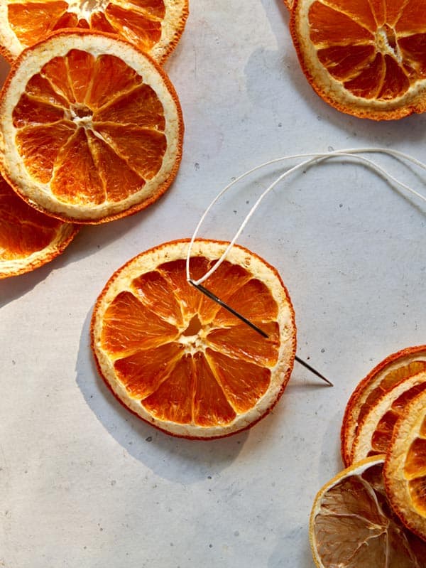 Making a citrus garland with a needle and twine.