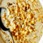 Creamed corn in a bowl with a spoon in it on a table.