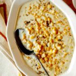 Creamed corn in a bowl with a spoon in it on a table.