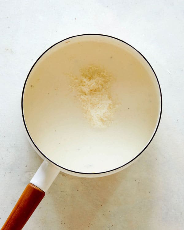Half and half with parmesan in a skillet to make creamed corn.
