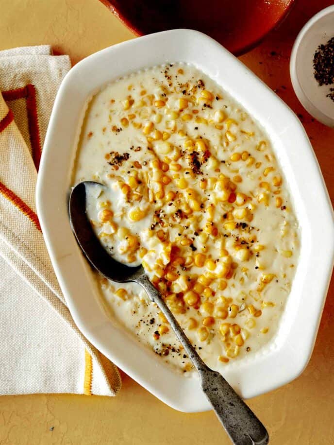 Creamed corn in a bowl with a spoon in it on a table.