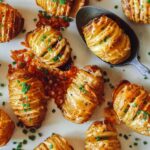 Cheesy Hasselback potatoes on a platter with a spoon.