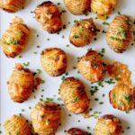 Hasselback potatoes with cheese on top and sprinkled with chives.