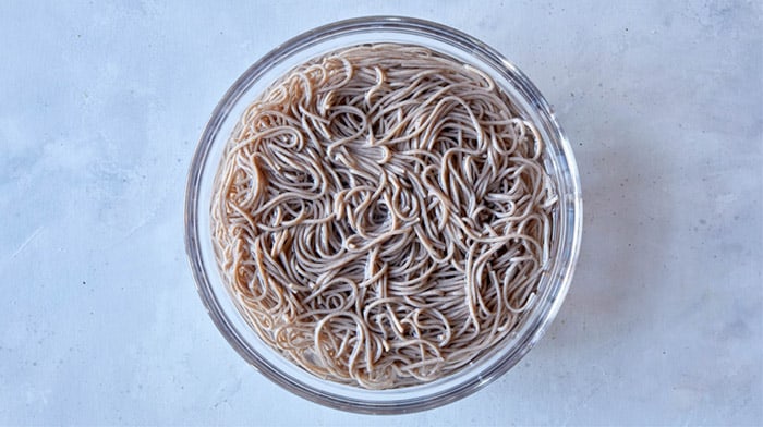 Soba noodles soaking in a bowl with water.