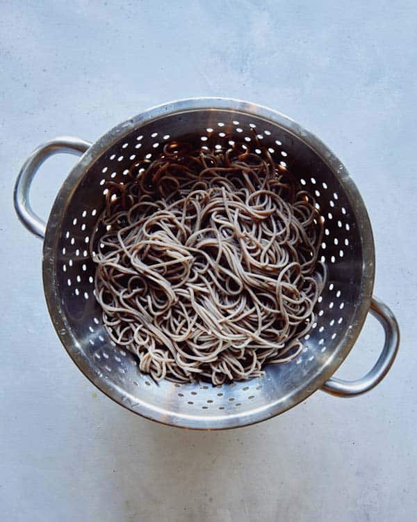 Boiled and drained soba noodles in a colander.