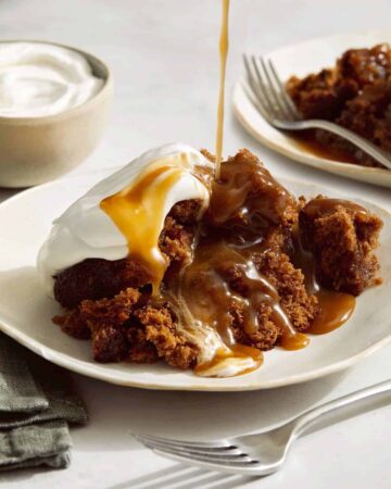 Sticky toffee pudding spooned onto a plate and drizzled with sauce.