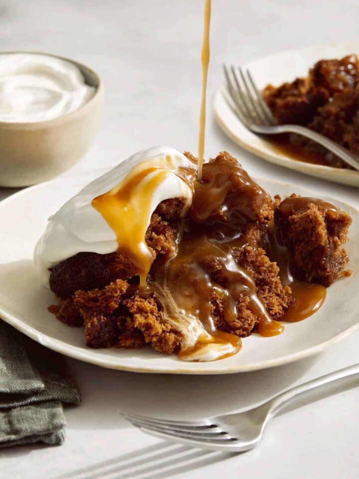 Sticky toffee pudding spooned onto a plate and drizzled with sauce, a perfect Valentines day dessert. 