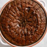 Sticky toffee pudding in a baking dish with sauce over it.