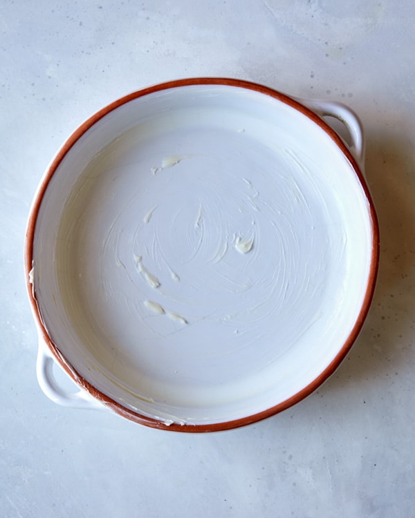 A greased baking dish for sticky toffee pudding.