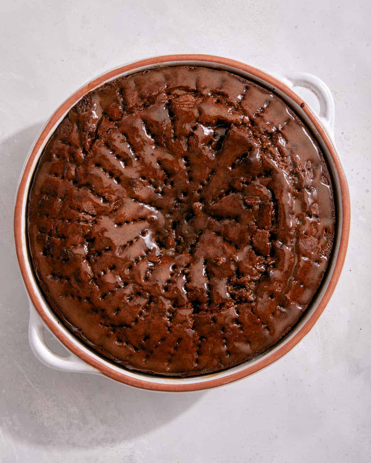 Sticky toffee pudding in a baking dish with sauce over it.