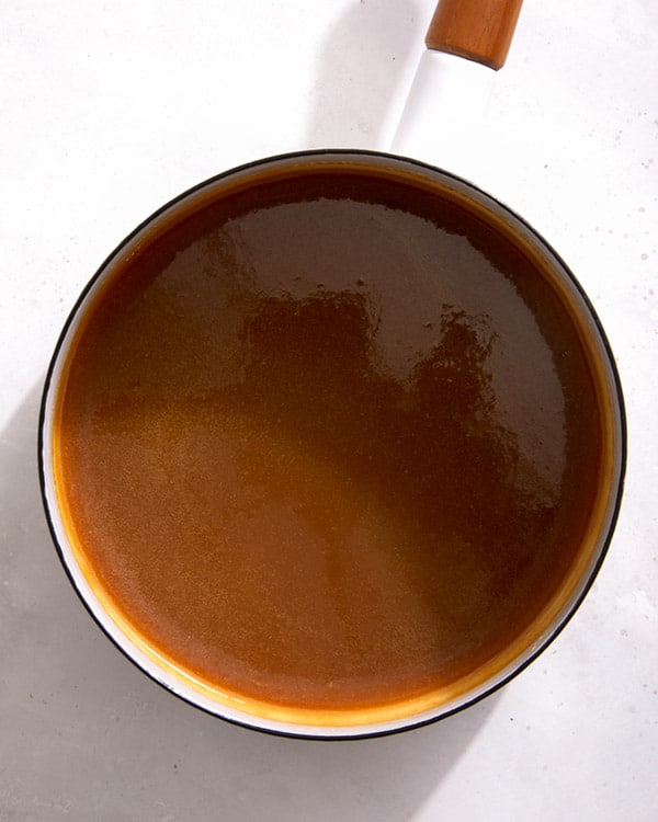 A pot full of sticky toffee pudding sauce.