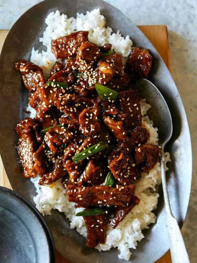 Mongolian beef recipe on a platter with a spoon in it.