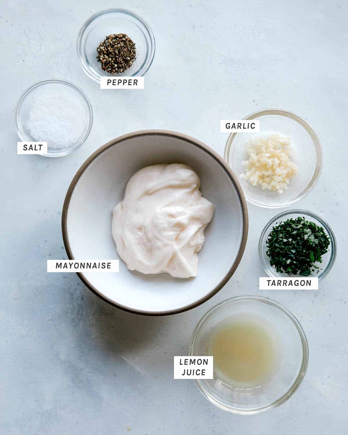 Ingredients for a tarragon aioli all laid on on a kitchen surface.