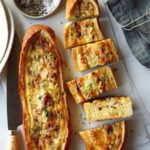 Two baked egg boats on a surface and one cut up.