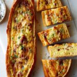 Two baked egg boats on a surface and one cut up.