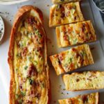 Two baked egg boats on a surface and one cut up.