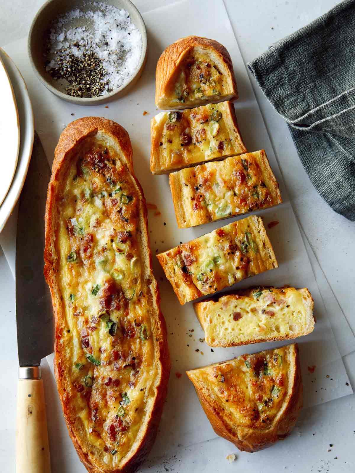 Two baked egg boats on a surface and one cut up. 