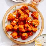 Buffalo cauliflower recipe on a plate with beers next to it.