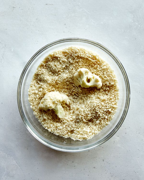 Buffalo cauliflower being dredged in breadcrumbs.