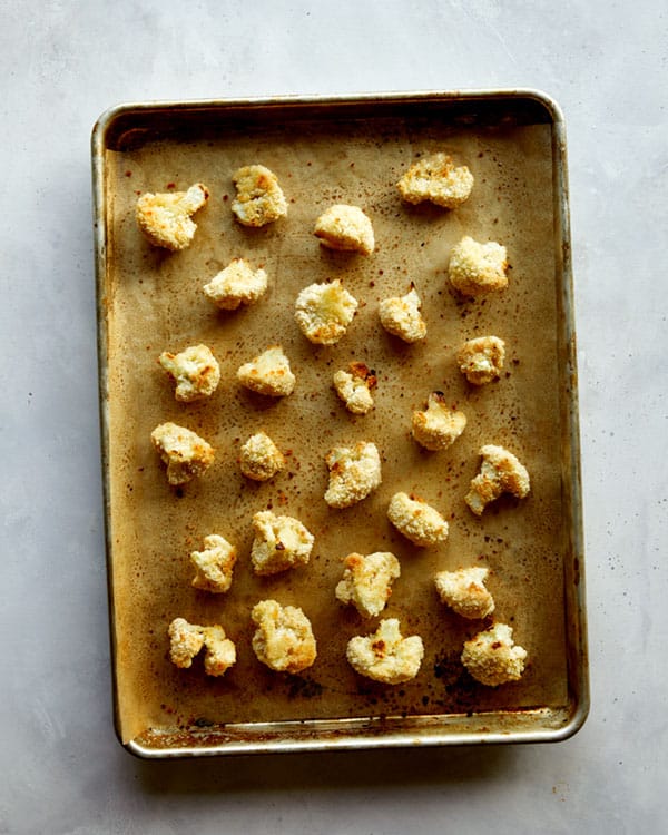 Cauliflower florets baked on a baking sheet for buffalo cauliflower.