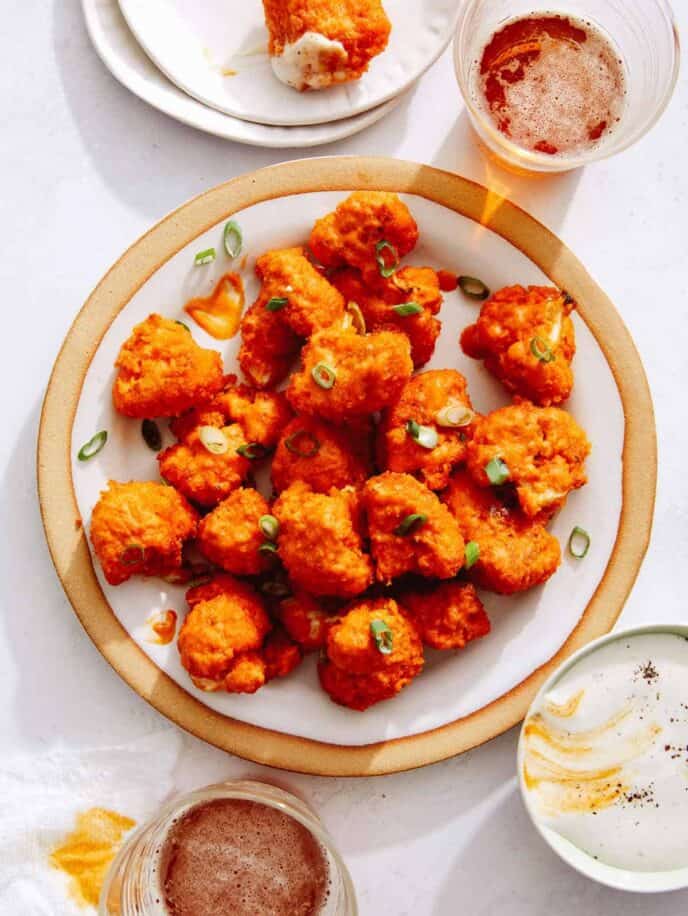 Buffalo cauliflower on a place with dipping sauce next to it.