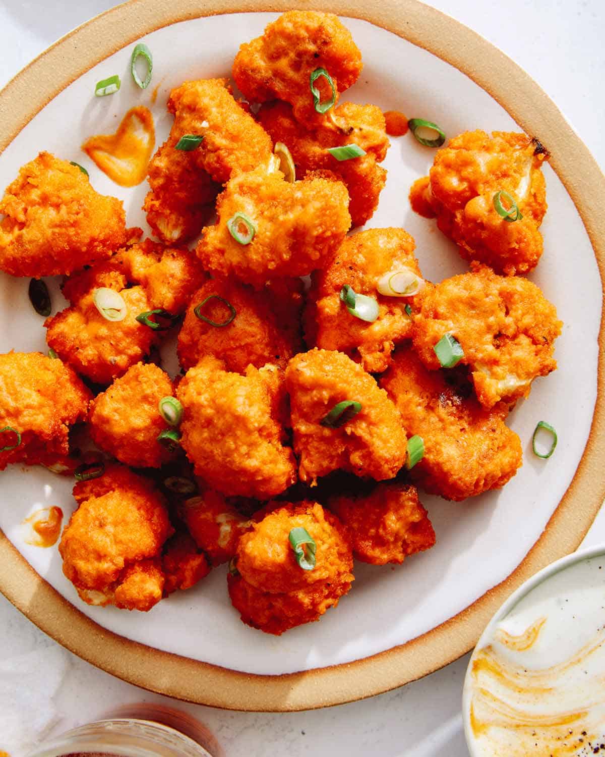 Buffalo cauliflower on a place with dipping sauce next to it.