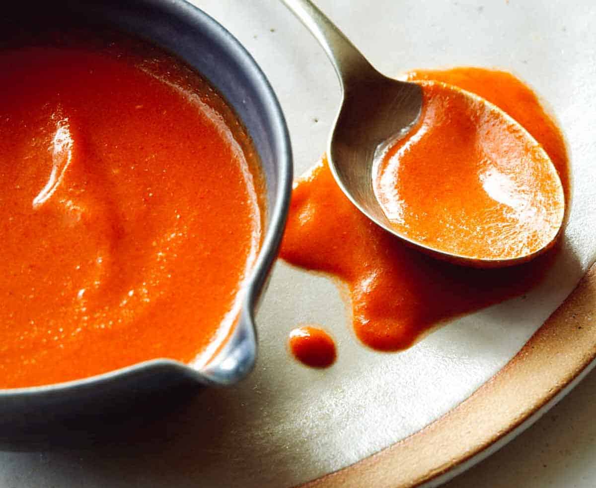 Buffalo sauce in bowl with a spoon. 