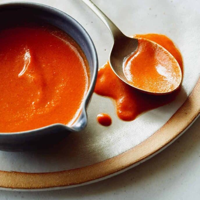 Buffalo sauce recipe in a bowl with a spoon next to it.