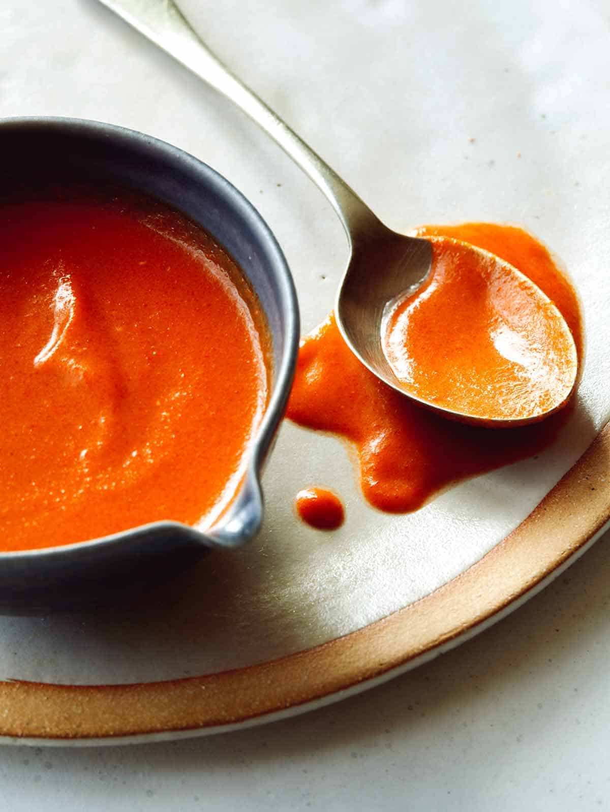 Buffalo sauce recipe in a bowl with a spoon next to it.