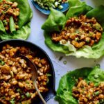 Chicken lettuce wraps with lettuce and chicken in them on the side.